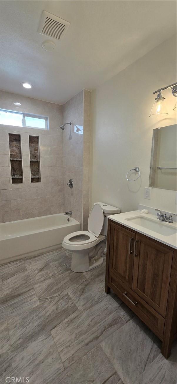 full bathroom with vanity, toilet, and tiled shower / bath