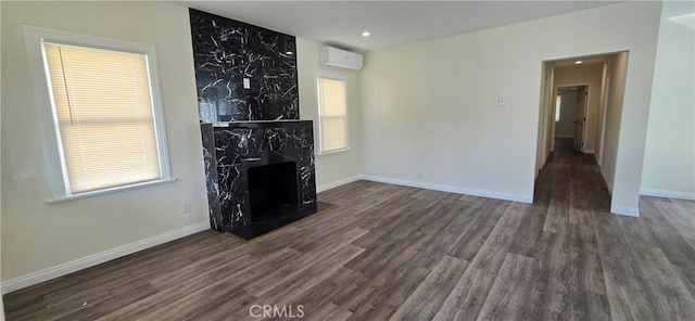 unfurnished living room with dark hardwood / wood-style floors, a fireplace, and a wall unit AC