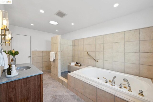 bathroom with vanity, tile walls, tile patterned floors, and plus walk in shower