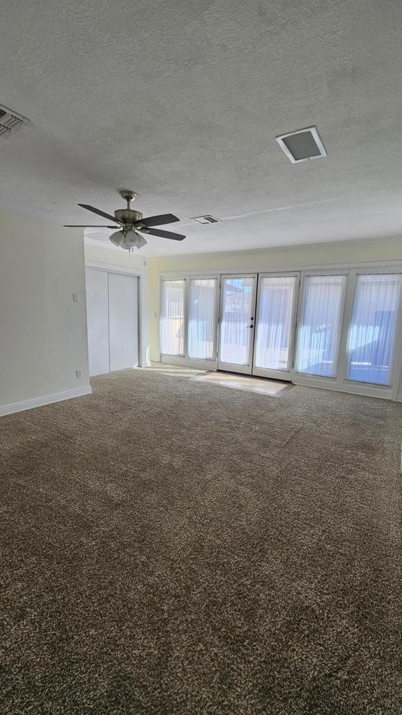 carpeted empty room with ceiling fan and a textured ceiling