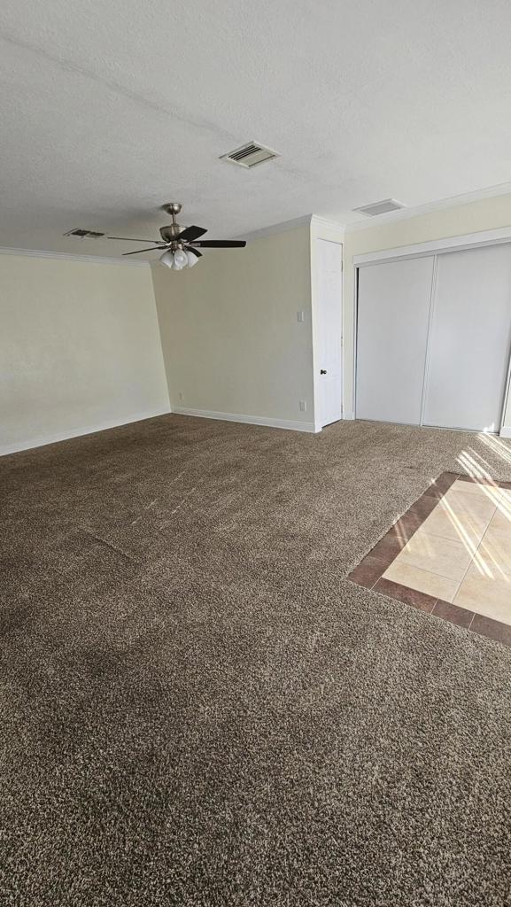 unfurnished room featuring ceiling fan, carpet floors, and a textured ceiling