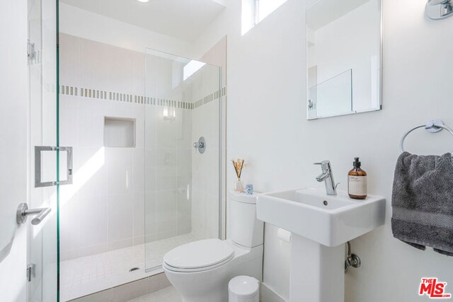 bathroom featuring toilet and a shower with shower door