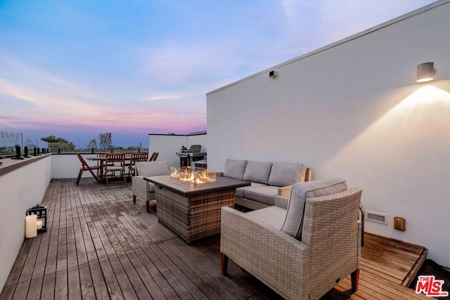 deck at dusk with an outdoor living space with a fire pit