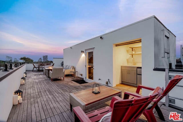 deck at dusk featuring an outdoor living space and sink