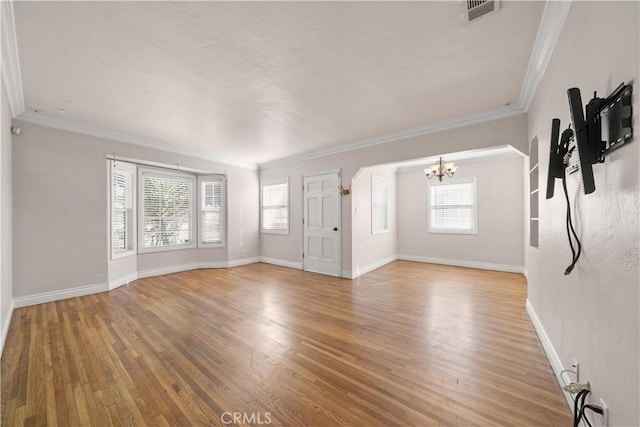 unfurnished living room with crown molding, hardwood / wood-style floors, and a notable chandelier