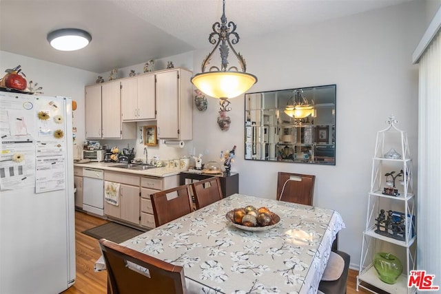 kitchen with light hardwood / wood-style floors, sink, white appliances, and decorative light fixtures