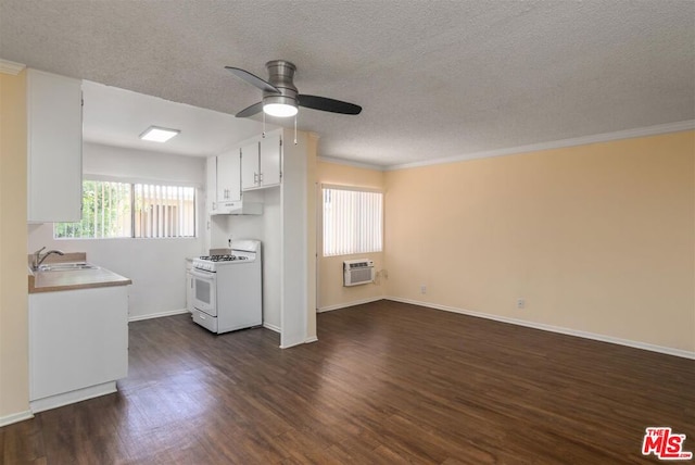 kitchen featuring an AC wall unit, white cabinetry, sink, dark hardwood / wood-style flooring, and gas range gas stove