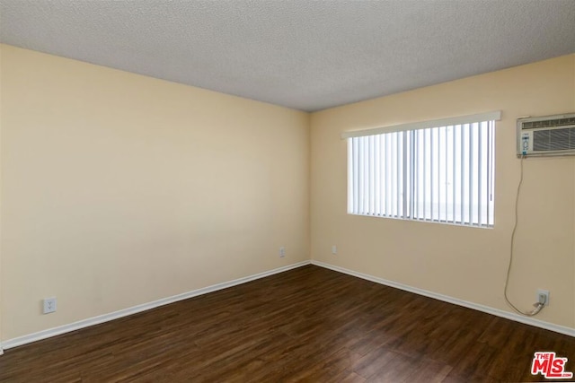 spare room featuring dark hardwood / wood-style floors, a wall mounted AC, and a textured ceiling