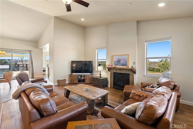 living room with plenty of natural light, light wood-type flooring, high vaulted ceiling, and a fireplace