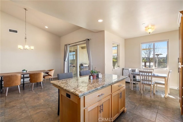 kitchen with a kitchen island, pendant lighting, lofted ceiling, light stone counters, and an inviting chandelier