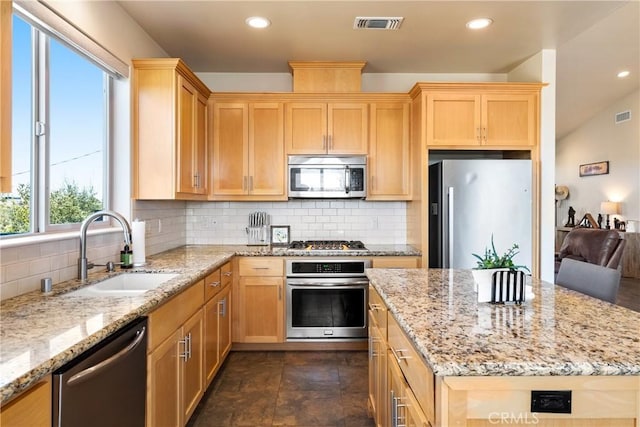 kitchen featuring appliances with stainless steel finishes, light stone countertops, sink, and backsplash