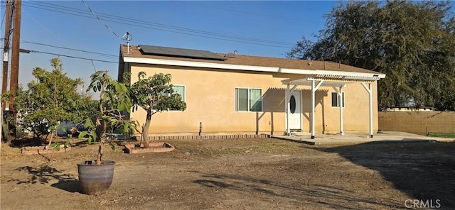 rear view of house featuring a pergola and solar panels