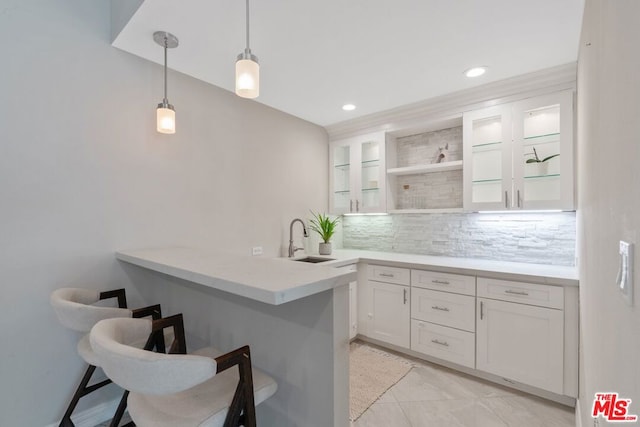 kitchen with white cabinetry, kitchen peninsula, sink, and a breakfast bar area