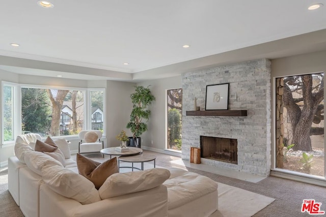 living room featuring a healthy amount of sunlight, light colored carpet, a fireplace, and a tray ceiling