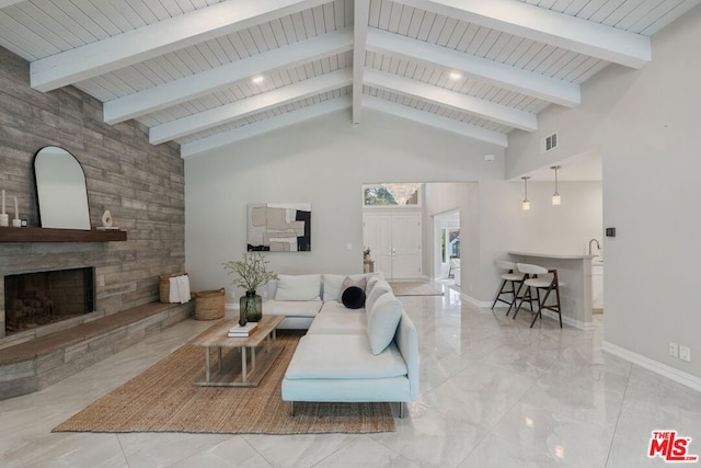 living room featuring beamed ceiling, a stone fireplace, and high vaulted ceiling