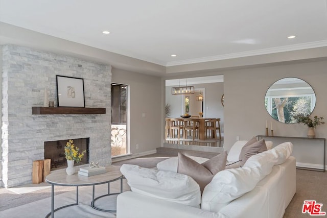 living room featuring ornamental molding, a stone fireplace, and a notable chandelier