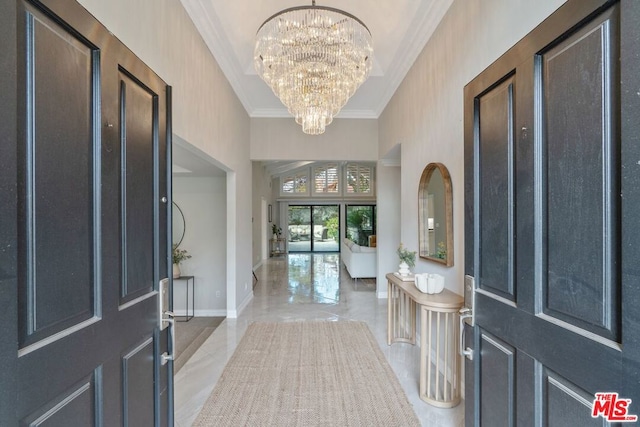 foyer featuring a notable chandelier, ornamental molding, and a high ceiling