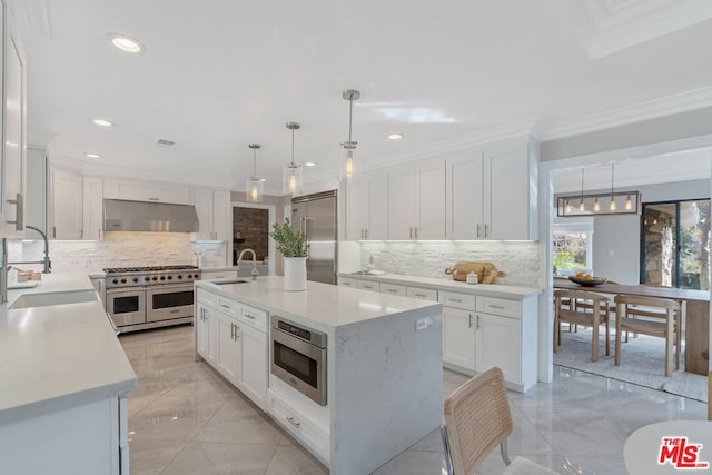 kitchen with pendant lighting, sink, a kitchen island with sink, built in appliances, and extractor fan