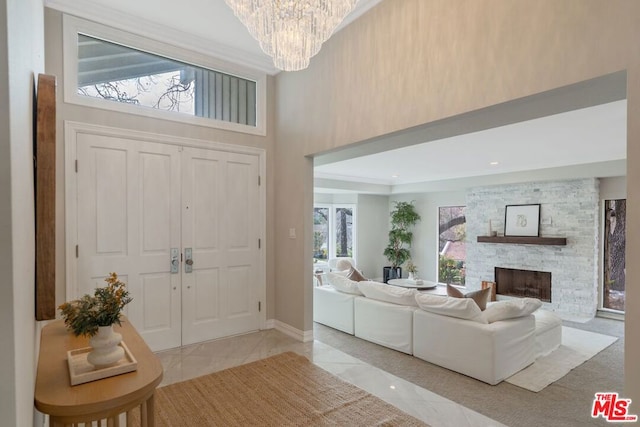 tiled foyer entrance with a stone fireplace, a towering ceiling, and an inviting chandelier