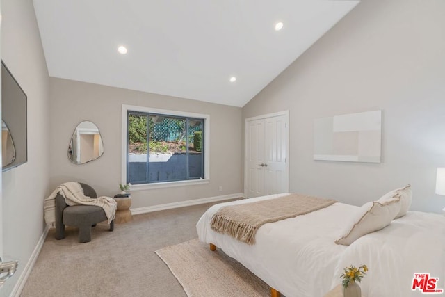 bedroom featuring a closet, high vaulted ceiling, and light carpet