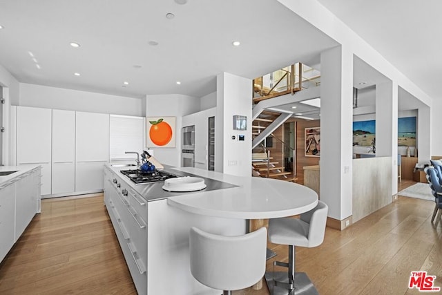 kitchen featuring white cabinetry, appliances with stainless steel finishes, a center island, and light wood-type flooring