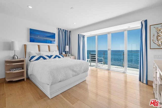 bedroom with a water view, access to exterior, and light hardwood / wood-style floors