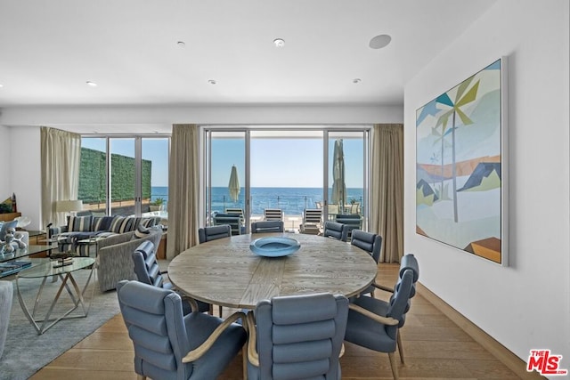 dining space with a water view and light hardwood / wood-style flooring