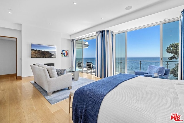 bedroom featuring a water view, access to outside, and light hardwood / wood-style floors