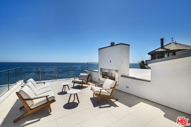 view of patio / terrace with a water view and an outdoor living space with a fireplace