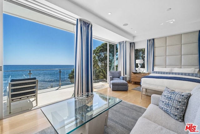 bedroom featuring a water view, access to exterior, and light wood-type flooring