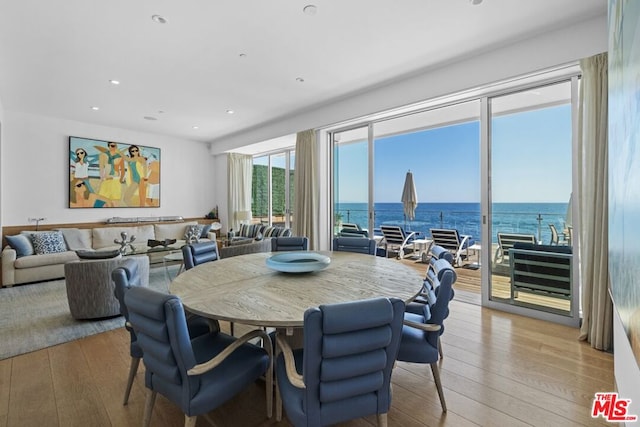 dining room with a water view and light hardwood / wood-style flooring