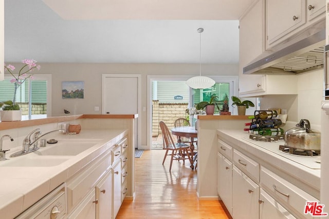 kitchen with decorative light fixtures, white cabinetry, sink, light wood-type flooring, and white gas cooktop