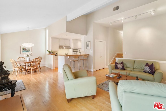 living room with vaulted ceiling, rail lighting, and light wood-type flooring