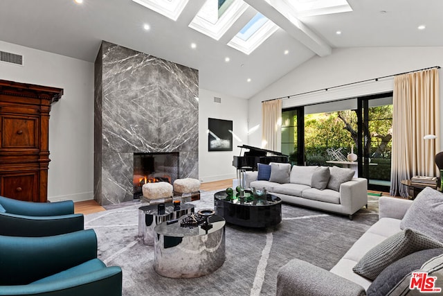 living room with a fireplace, vaulted ceiling with skylight, and hardwood / wood-style floors