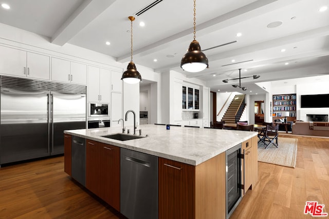 kitchen with white cabinetry, sink, built in appliances, and beverage cooler