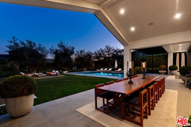 patio terrace at dusk featuring a lawn