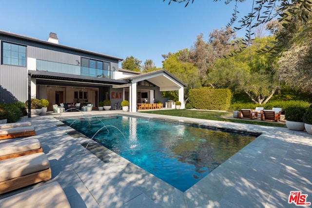 back of house featuring pool water feature, a balcony, outdoor lounge area, and a patio