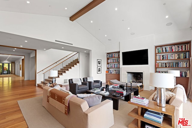 living room featuring beamed ceiling, high vaulted ceiling, light wood-type flooring, and built in shelves