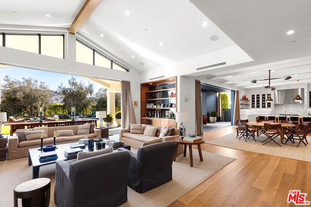 living room with light hardwood / wood-style flooring, high vaulted ceiling, and beamed ceiling