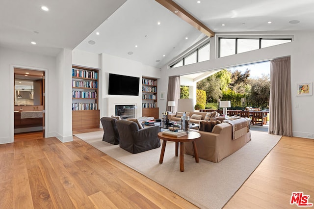 living room featuring high vaulted ceiling, beam ceiling, built in features, and light hardwood / wood-style floors