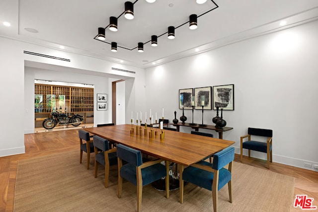 dining area with crown molding and light parquet flooring