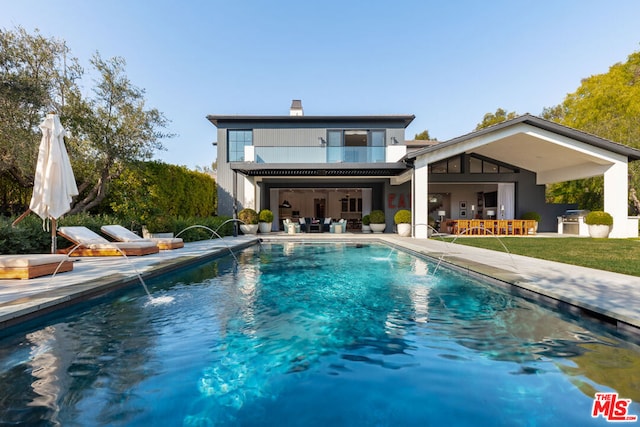 rear view of property with a patio, pool water feature, and a bar