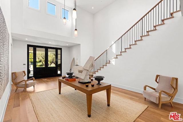 foyer featuring a high ceiling, light wood-type flooring, and french doors