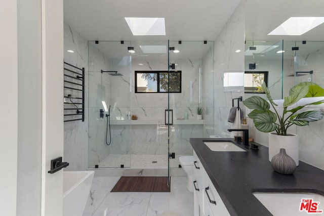 full bathroom with independent shower and bath, vanity, toilet, and a skylight