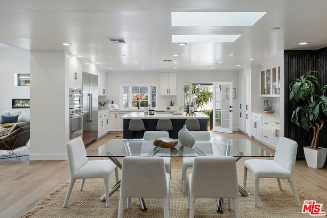 dining space featuring a skylight and light wood-type flooring