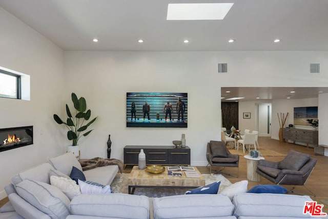 living room featuring wood-type flooring and a skylight