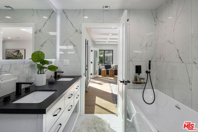 bathroom with hardwood / wood-style flooring, vanity, and a tub to relax in