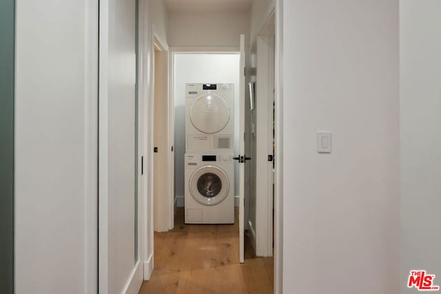 laundry room with stacked washer and dryer and light wood-type flooring