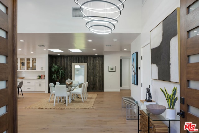 dining room featuring a notable chandelier, a skylight, and light wood-type flooring