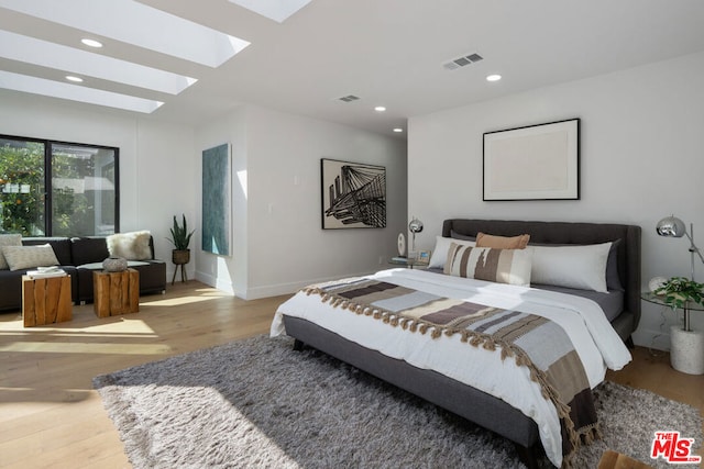 bedroom with a skylight and light wood-type flooring